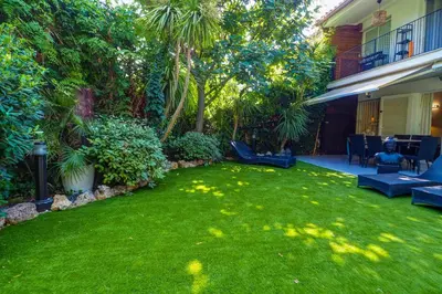 a yard with a green lawn with benches and trees at Beach Apartment Garden Vinyet by Hello Homes Sitges in Sitges
