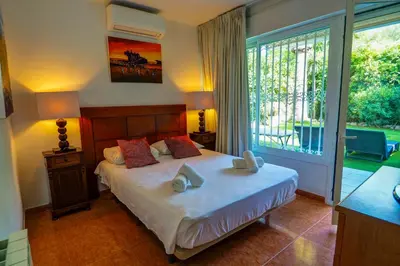 a bedroom with a bed and a large window at Beach Apartment Garden Vinyet by Hello Homes Sitges in Sitges