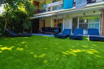 a yard with blue chairs on the grass at Beach Apartment Garden Vinyet by Hello Homes Sitges in Sitges