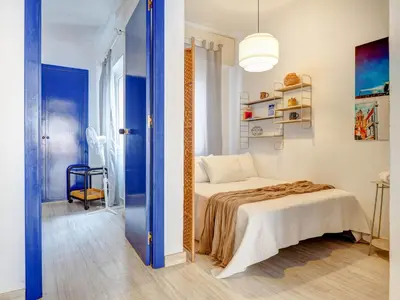 a bedroom with a bed and a blue door at Velero Attic by Hello Homes Sitges in Sitges