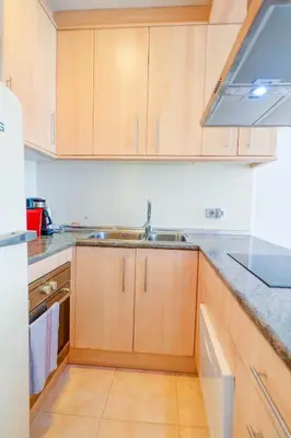 a kitchen with wooden cabinets and a sink at The Loft by Hello Homes Sitges in Sitges