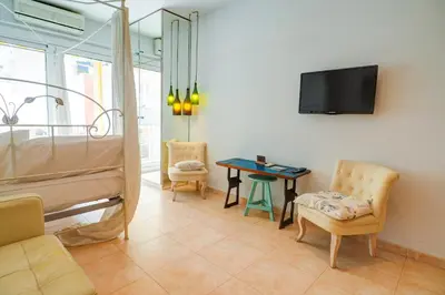 a room with a bed and a table and a tv at The Loft by Hello Homes Sitges in Sitges