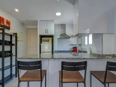 a kitchen with a counter with chairs and a counter top at Los Globos Beach Studio by Hello Homes Sitges in Sitges