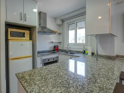 a kitchen with white appliances and a granite counter top at Los Globos Beach Studio by Hello Homes Sitges in Sitges