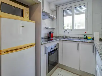 a kitchen with white cabinets and a sink and a window at Los Globos Beach Studio by Hello Homes Sitges in Sitges