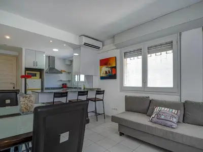 a living room with a couch and a kitchen at Los Globos Beach Studio by Hello Homes Sitges in Sitges