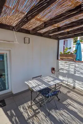 a table on a porch with a chair on a patio at Harbour terraces by Hello Homes Sitges in Sitges
