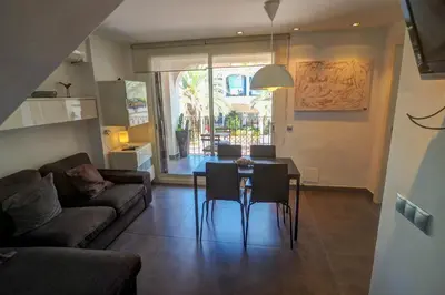 a living room with a couch and a table and chairs at Harbour terraces by Hello Homes Sitges in Sitges