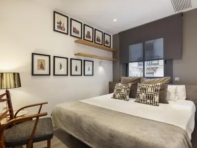 a bedroom with a large white bed and a chair at Click&Flat Luxury cabanyes in Barcelona