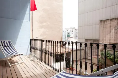 a balcony with a chair and a flag on a building at LUXURY BARCELONA CENTRAL CITY COSY 3 BEDROOM APARTMENT WITH PRIVATE TERRACE in Barcelona