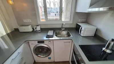a small kitchen with a washing machine and a sink at Opening Doors Sagrada Familia in Barcelona