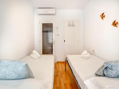 two beds in a small room with white walls at Sebastian Terrace Apartment by Hello Homes Sitges in Sitges