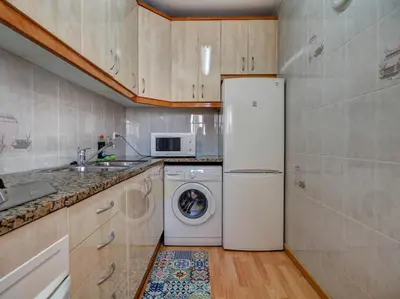 a kitchen with a refrigerator and a washing machine at Sebastian Terrace Apartment by Hello Homes Sitges in Sitges