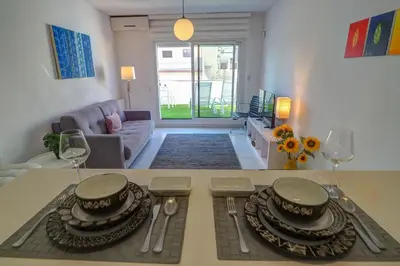 a living room with a table with plates and wine glasses at White Penthouse by Hello Homes Sitges in Sitges