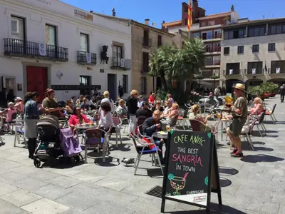 a crowd of people sitting at tables in a courtyard at COLIBRI in Calella