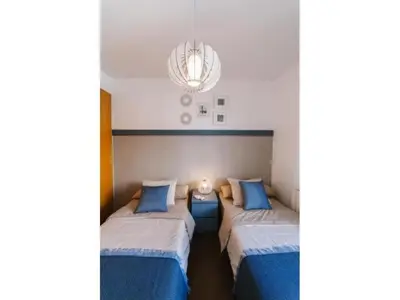 a bedroom with two beds and a chandelier at Sitges Spaces Deluxe Beach Apartment- 3 Bedroom, 2 Bathroom, Next to Beach, Sleeps 6 in Sitges