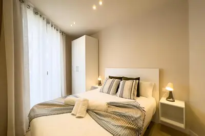 a bedroom with a bed with white sheets and a window at Barcelona Touch Apartments - Progres in Hospitalet de Llobregat