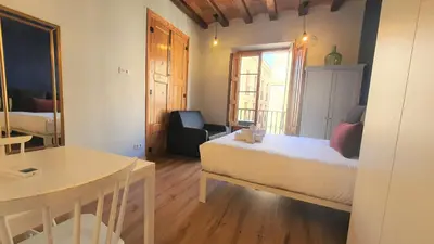 a bedroom with a bed and a chair and a table at Barrio Gotico Apartments Ferran in Barcelona