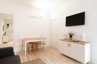 a living room with a table and a tv on a wall at Apartamento NUEVO con encanto en SAGRADA FAMILIA in Barcelona