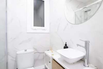 a white bathroom with a sink and a mirror at Apartamento NUEVO con encanto en SAGRADA FAMILIA in Barcelona