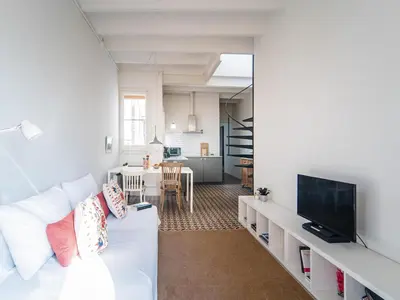 a living room with a white couch and a tv at White penthouse in Barcelona