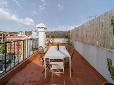 a balcony with a table and chairs on a roof at White penthouse in Barcelona