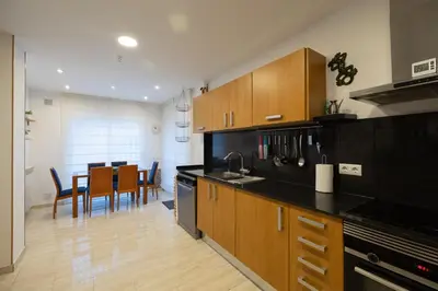 a kitchen with wooden cabinets and a dining room at Stay U-nique Villa Portimar in Arenys de Mar