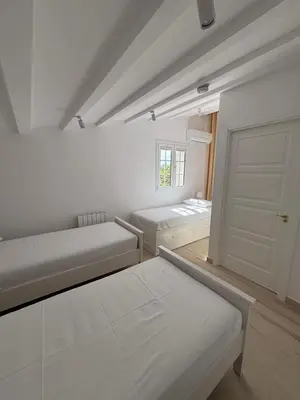 a white room with two beds and a door at Bio Resort Mediterráneo in San Martín Sarroca