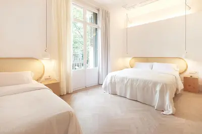 two beds in a white room with a window at The MO House in Barcelona