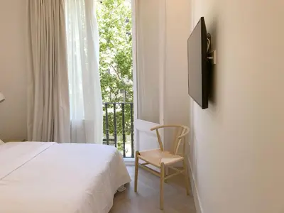 a bedroom with a bed and a chair and a window at The MO House in Barcelona