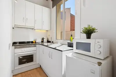 a white kitchen with white cabinets and a microwave at Lodging Apartments Barceloneta Beach Studio 32 in Barcelona