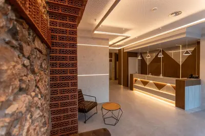 a lobby with a chair and a table and a wall at Art Apartments BCN in Castelldefels