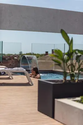 a woman is sitting in a swimming pool at Art Apartments BCN in Castelldefels