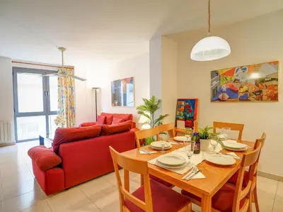 a living room with a table and a red couch at Apartamento Burdeos by Hello Homes Sitges in Sitges