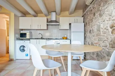 a kitchen with a table and chairs and a stone wall at Alcam Santa Monica in Barcelona