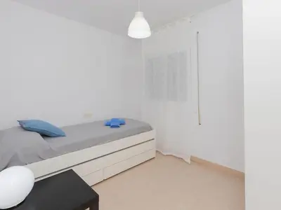 a white bedroom with a bed and a table at Apartment Blue Sea by Interhome in Cunit