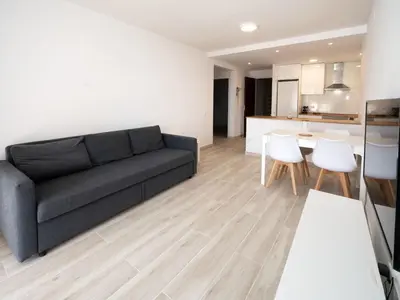 a living room with a black couch and a kitchen at Apartment Blue Sea by Interhome in Cunit