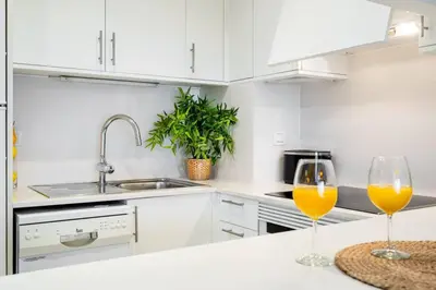 a white kitchen with two wine glasses on a counter at Lodging Apartments Monumumental in Barcelona