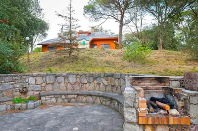 a stone wall in front of a house with a building at El Chalet del Montseny in Seva