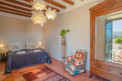 a bedroom with a bed and a chair and a window at Masia Victoria in Sant Pere de Ribes