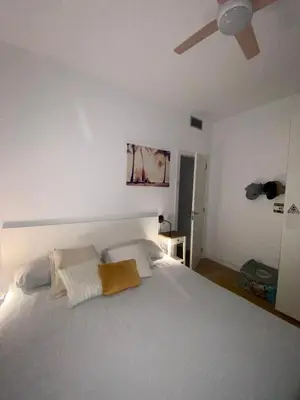 a bedroom with a white bed with a ceiling fan at Casa grande y céntrica con piscina en zona peatonal in Montgat