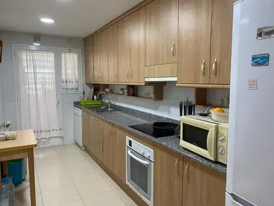 a kitchen with wooden cabinets and a microwave oven at Sitges Living Apartment in Sitges