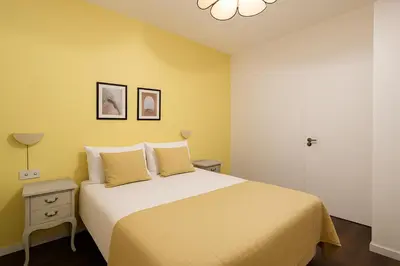 a bedroom with a large bed with yellow walls at Stay U-nique Apartments Estación del Norte in Barcelona