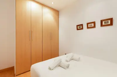 a bedroom with a white bed and wooden cabinets at Stay U-nique Apartments Terrassa in Barcelona