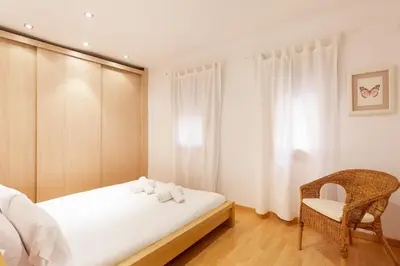 a bedroom with a white bed and a chair at Stay U-nique Apartments Terrassa in Barcelona