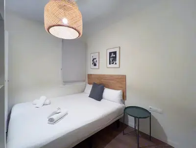 a small bedroom with a white bed and a stool at Stay U-nique Apartments Rocafort in Barcelona