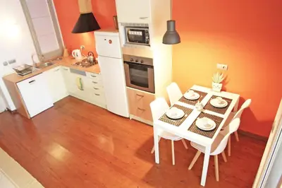 a kitchen with a table with white chairs and a kitchen with orange walls at Urban Loft Barcelona Diagonal super ubicación wifi in Barcelona