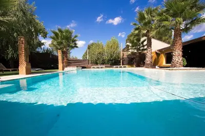 a large blue swimming pool with palm trees at Catalunya Casas Relax and Recharge - only 34km from Barcelona! in Rubí