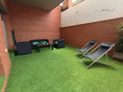 a patio with grass and chairs and a couch at Mazi Apartments Terrace in Mataró