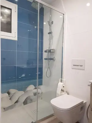 a bathroom with a glass shower with a toilet at Eros Apartament in Calella